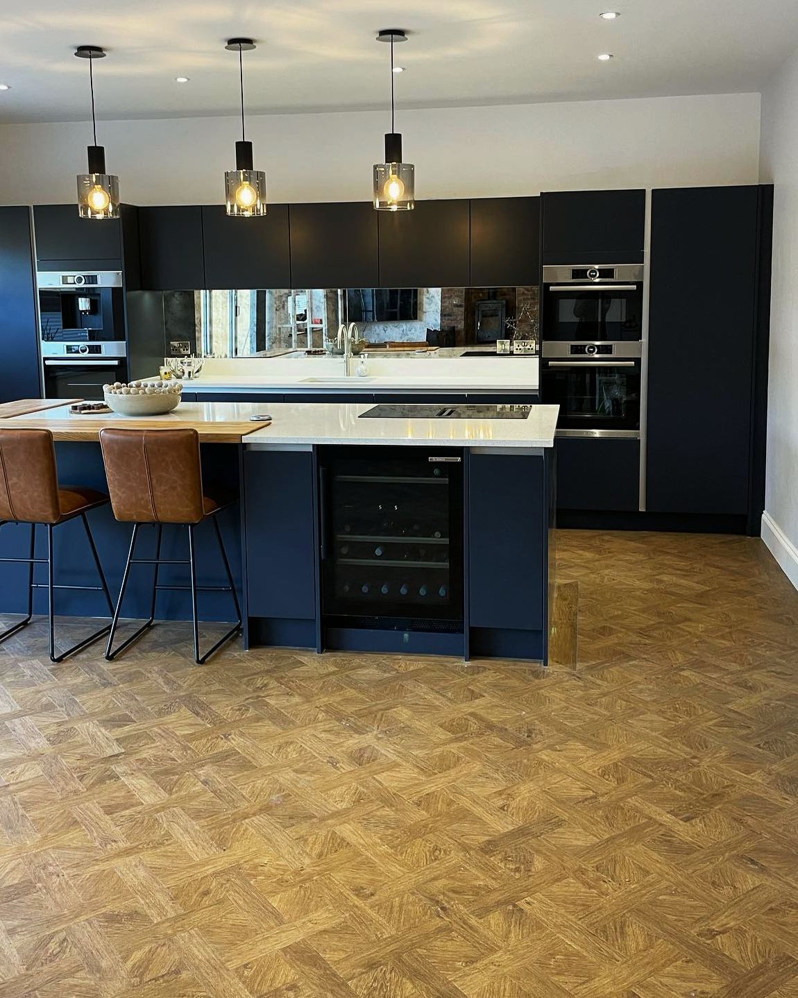 Mid blue kitchen with an island, quartz worktop and oak breakfast bar