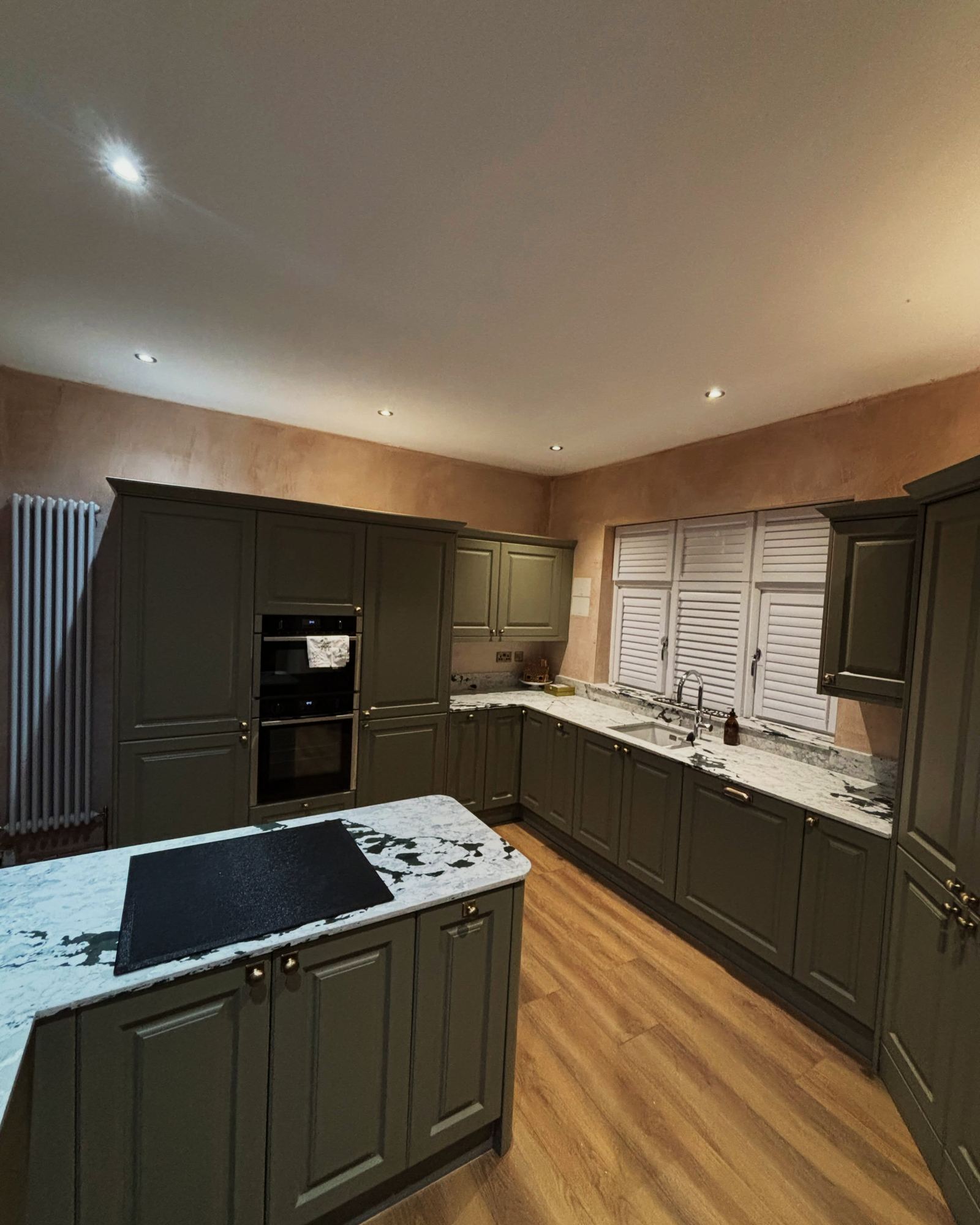 Olive green shaker kitchen with brass handles and a pale quartz worktop