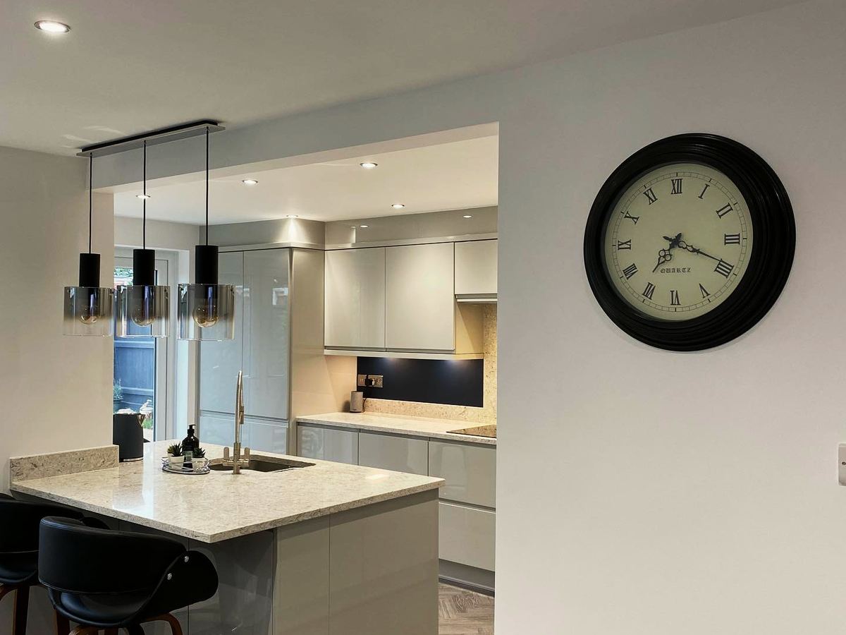 Open-plan gloss handleless kitchen with a quartz worktop, herringbone floor and French doors