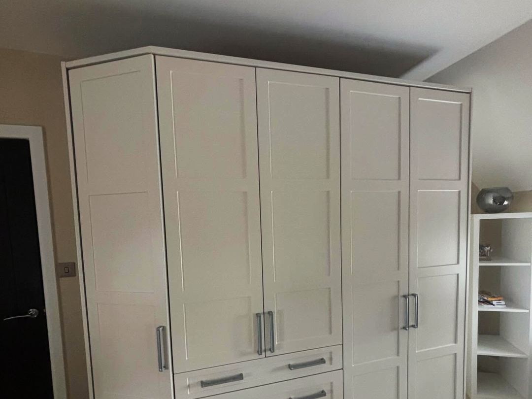 Ivory shaker fitted wardrobes running along a bedroom wall