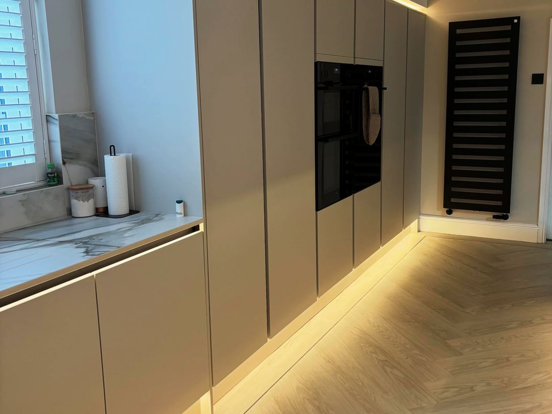 Taupe handleless kitchen with soft plinth lighting